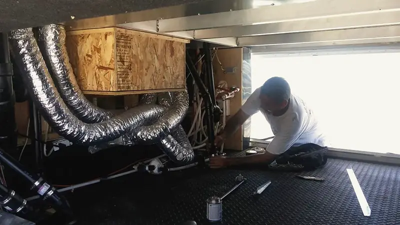 Technician rebuilding the ducting and framing inside a motorhome ceiling