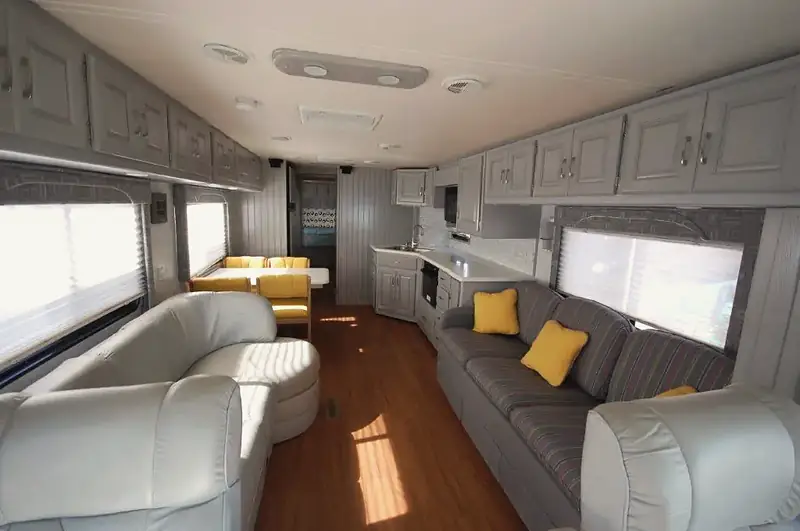 The same lounge after the remodel, with grey cabinets, leather sofas and a wood floor